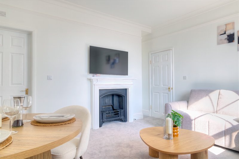 Bright living room with fireplace, TV, wooden dining table, sofa and potted plant