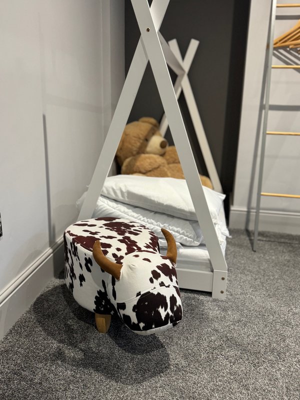 Child's teepee bed frame with cow-print storage ottoman and cushions