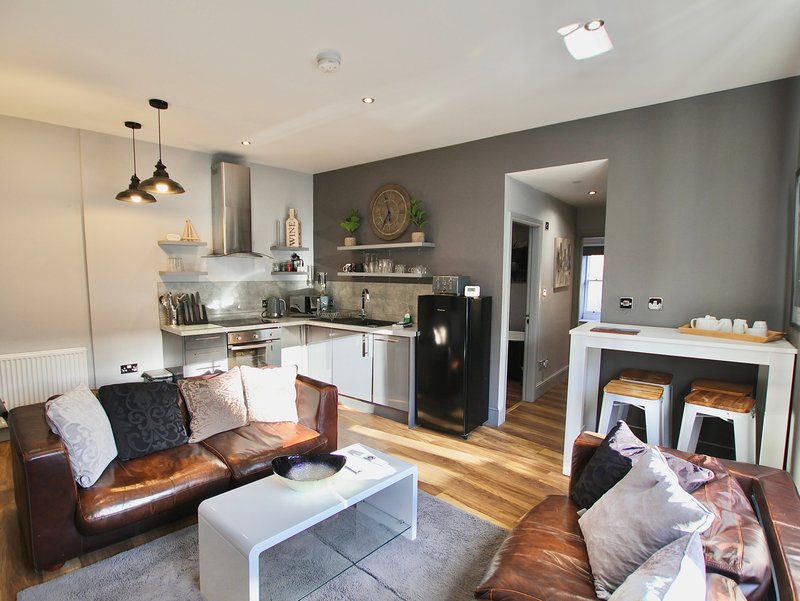 Open-plan living and kitchen area with leather sofa, white coffee table, and modern appliances
