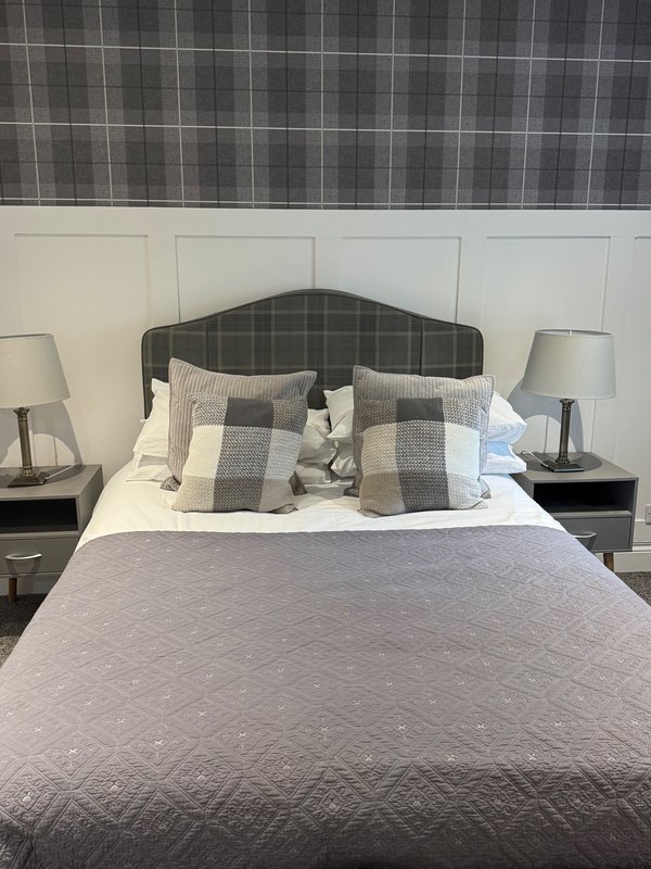 Modern bedroom with double bed, plaid headboard, patterned bedding and table lamps