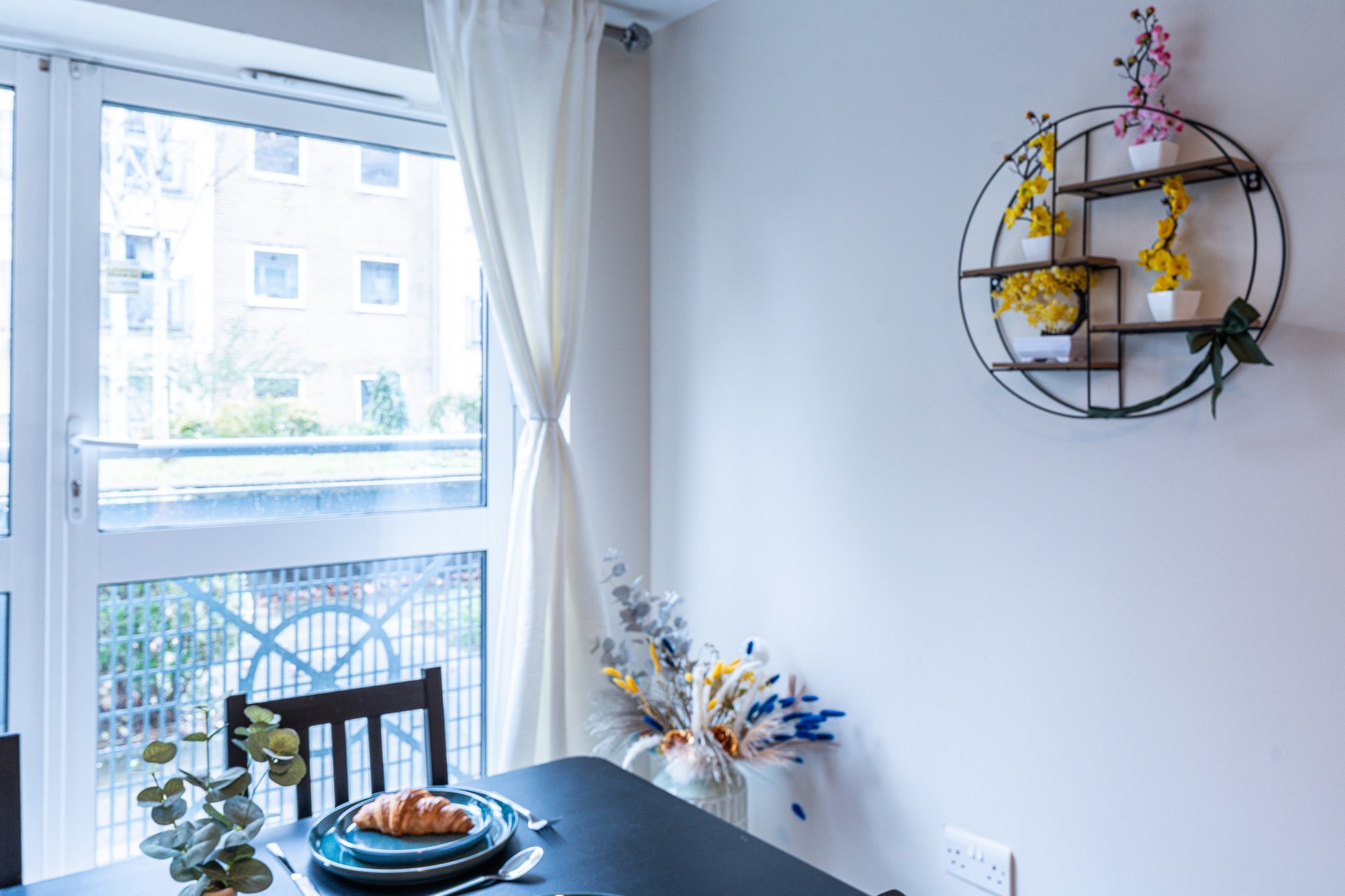 Dining area with table, chair, place setting and window overlooking residential street