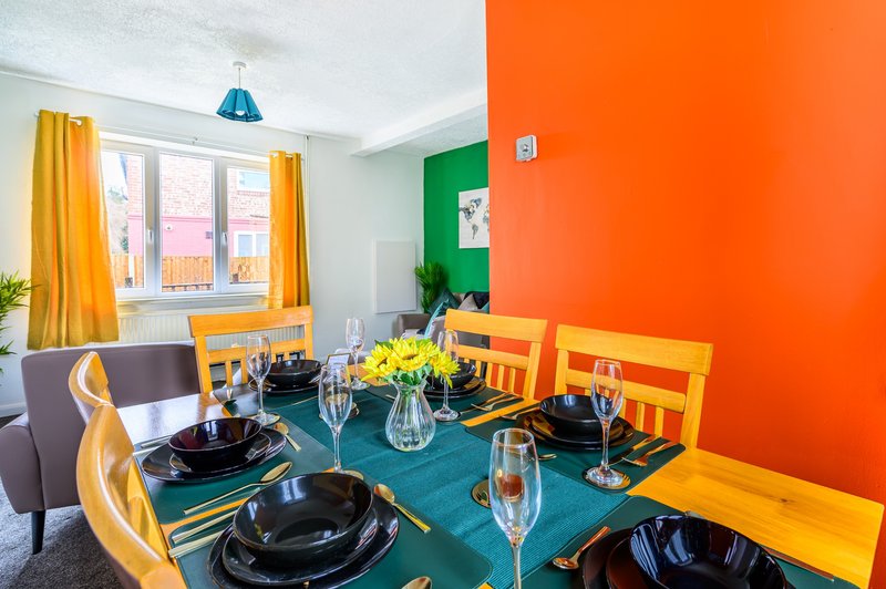 Colorful dining room with teal table, orange and yellow chairs, and bright accent walls