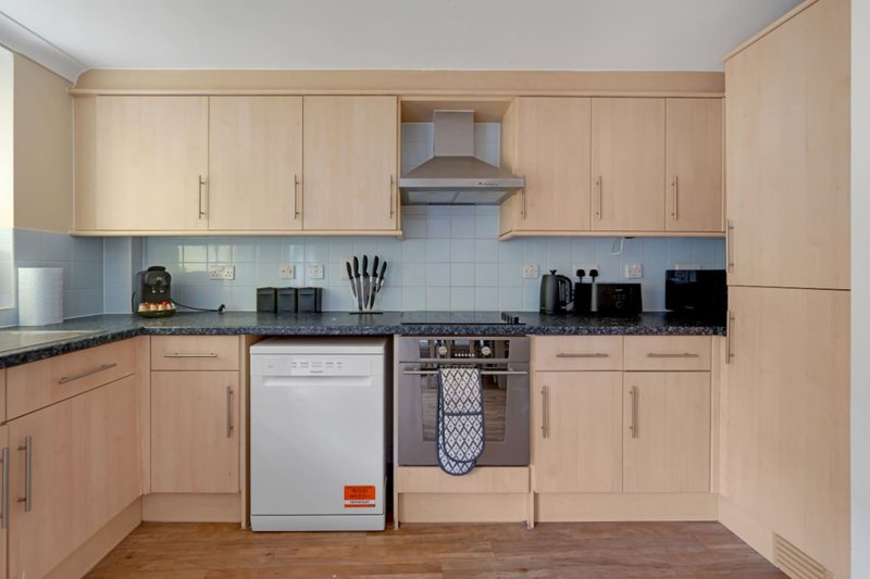 Modern kitchen with beige cabinetry, white subway tile backsplash, stainless steel appliances and wooden flooring