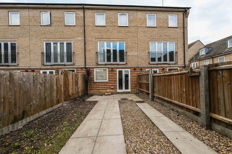 Modern brick townhouse with wooden fence, patio area and gravel garden
