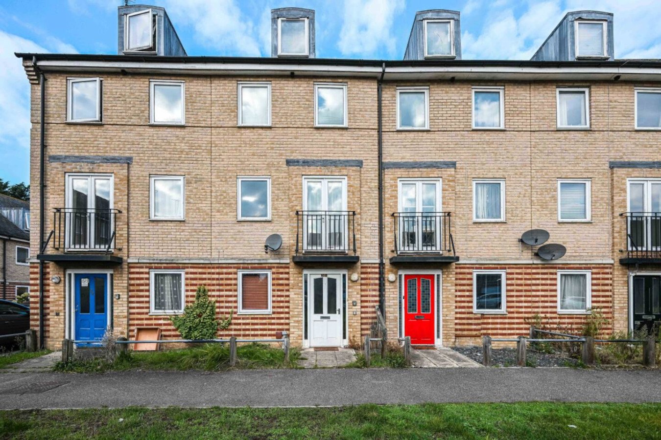 Brick and timber-clad terraced housing with colorful front doors and dormer windows