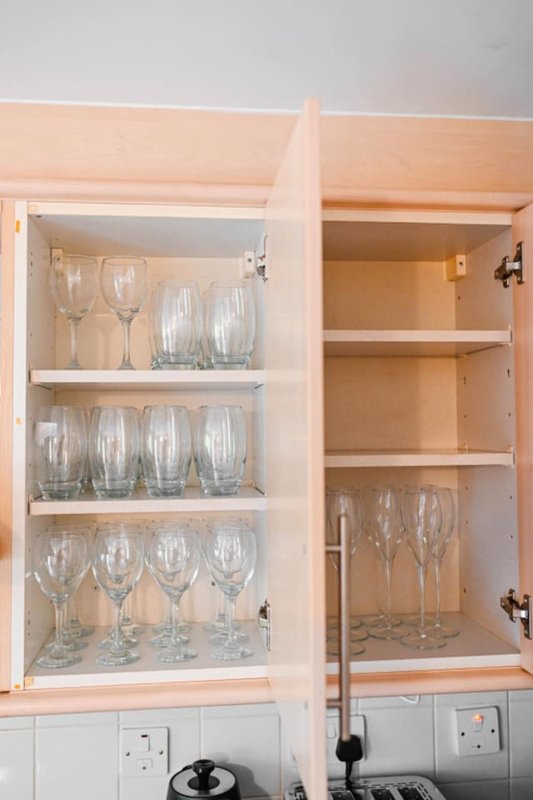 Kitchen cabinets with glass doors displaying wine glasses and drinking glasses on shelves