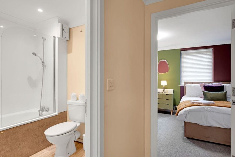 Bathroom with toilet, shower cubicle, and view into bedroom beyond