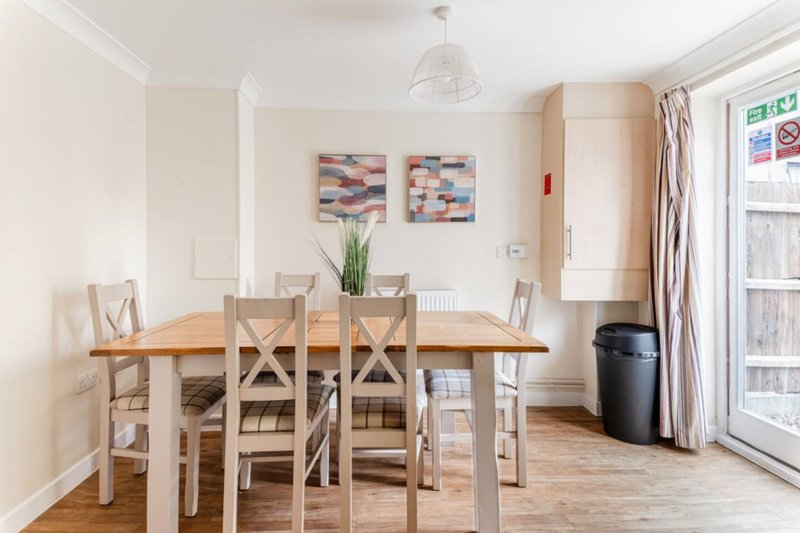 Dining room with wooden table, four cream chairs, and abstract wall art