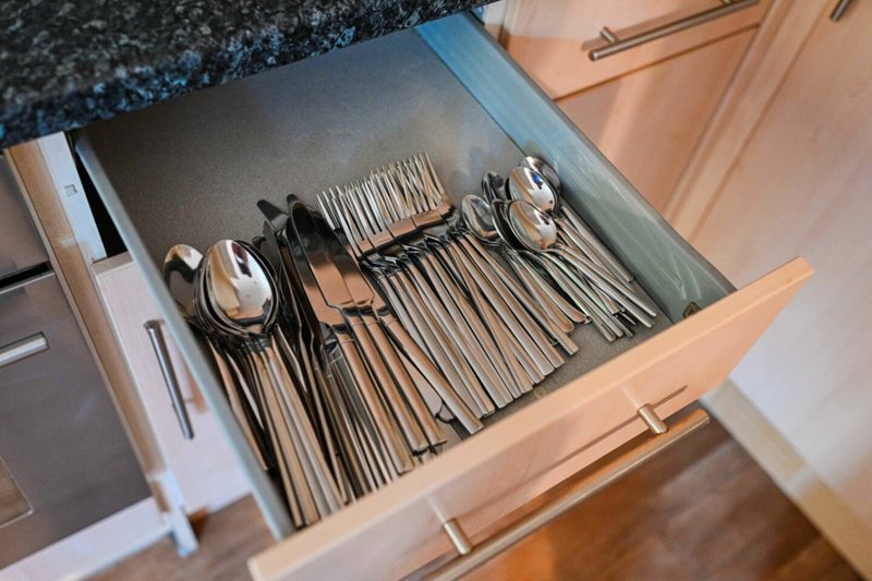 Open kitchen drawer with organized cutlery, forks, spoons and knives