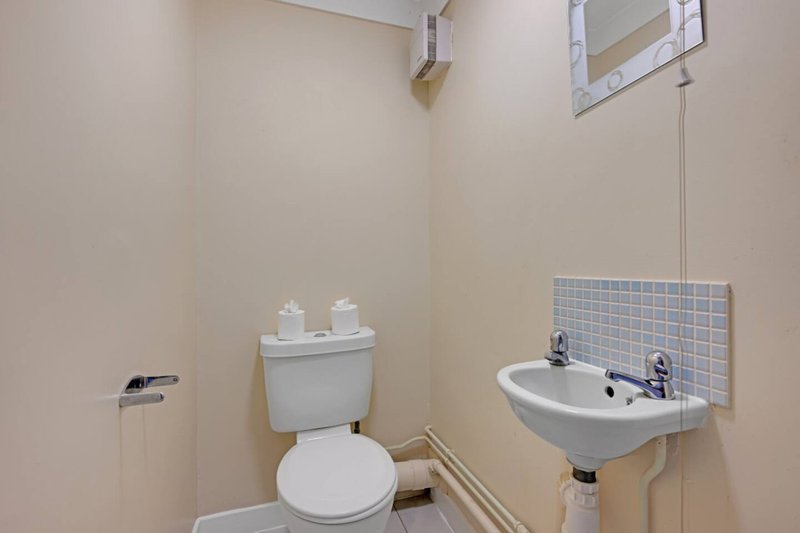 Small bathroom with toilet, wall-mounted sink, and tiled backsplash