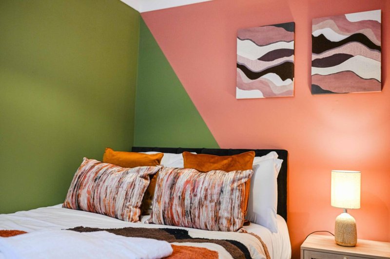 Modern bedroom with colorful accent wall, double bed, patterned pillows and bedside lamp