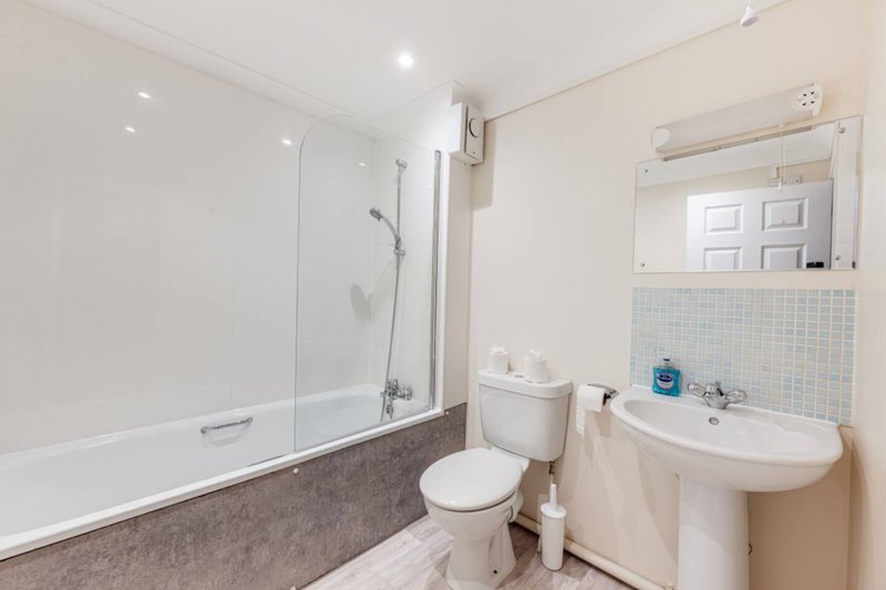 Clean bathroom with bathtub, shower screen, toilet, sink and mirror