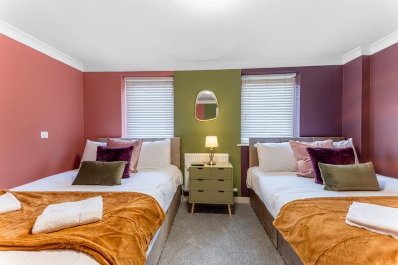 Twin bedroom with two wooden beds, colorful accent walls, shared nightstand and mirror