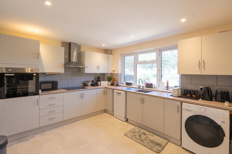 Modern kitchen with white cabinetry, stainless steel appliances, island counter and garden views