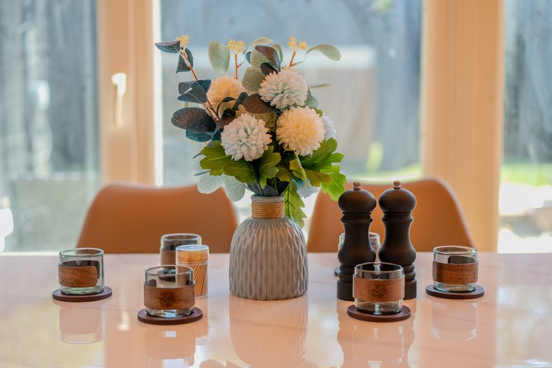 Styled table display with flower arrangement, candles and decorative objects by window