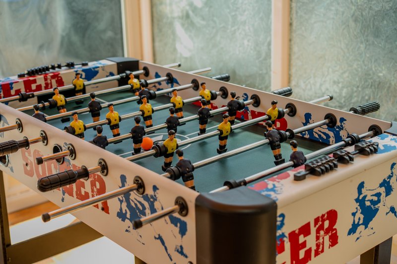 Foosball table with colored player figures and ball in bright room with windows