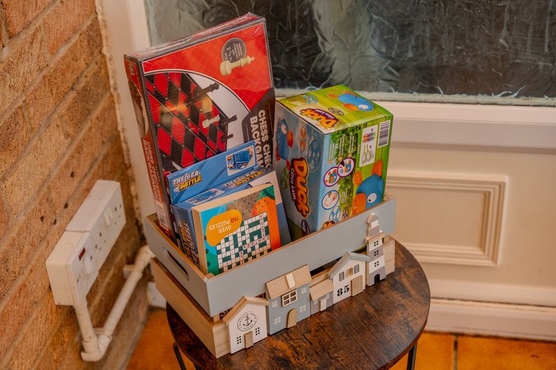 Wooden table with stacked board games and toys near window