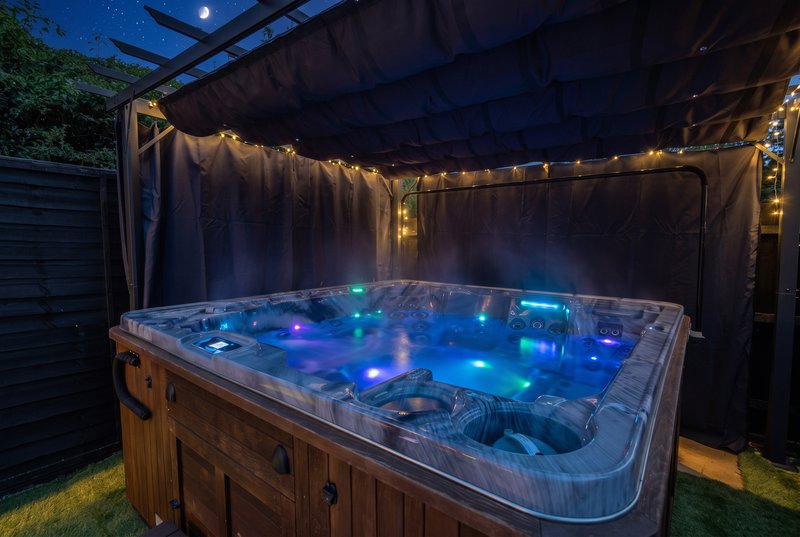 Outdoor hot tub with blue LED lighting under pergola at dusk
