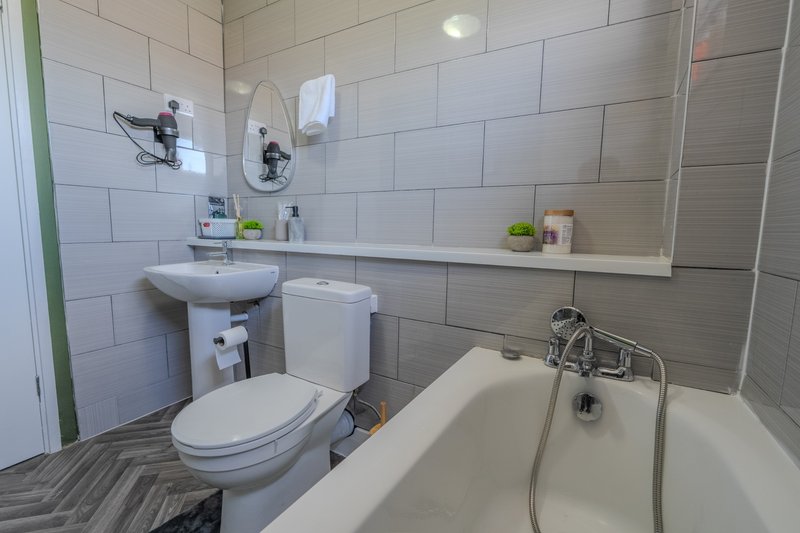Modern bathroom with white subway tile, pedestal sink, toilet, bathtub and shower fixtures