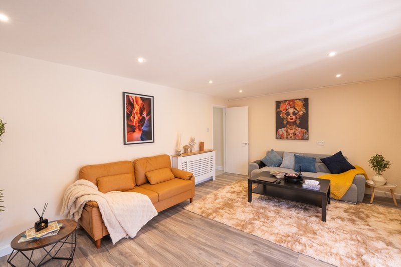 Open-plan living room with orange sofa, black coffee table, and second seating area