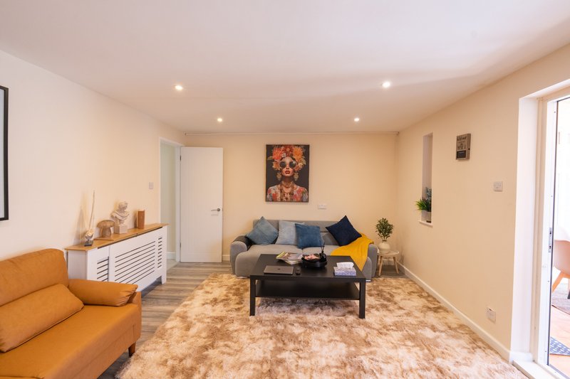 Bright living room with orange armchair, gray sofa, black coffee table and framed artwork