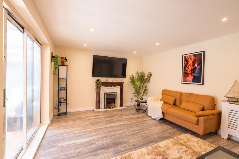 Spacious living room with orange sofa, fireplace, wall-mounted TV and patio doors