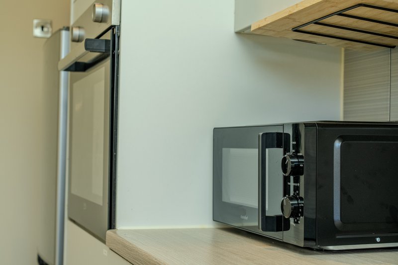 Kitchen counter with microwave, kettle, and wall-mounted shelving unit