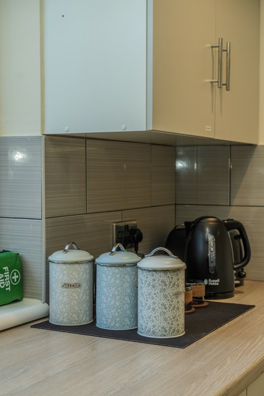 Kitchen counter with storage canisters, kettle, and small appliances under wall cabinets