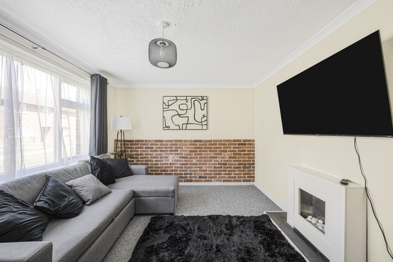 Modern living room with grey sofa, wall-mounted TV, brick feature wall and fireplace