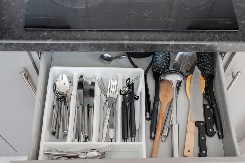 Kitchen drawer with organized utensils, cutlery, and cooking tools including knives and wooden handles