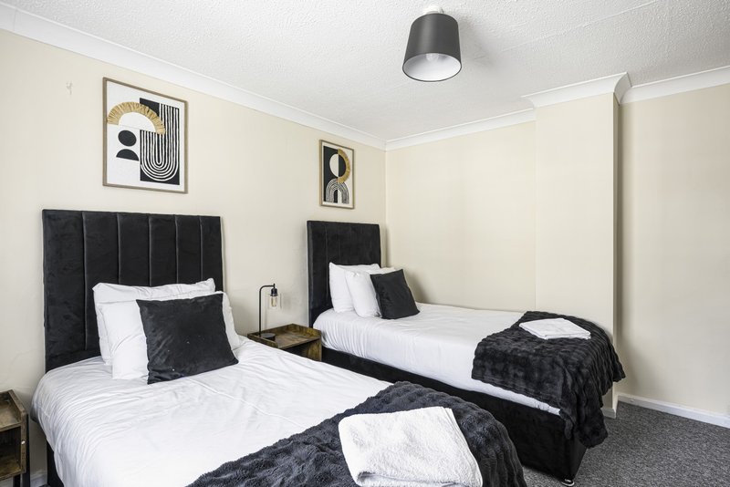 Twin bedroom with black upholstered headboards, white bedding, black throws, and modern wall art
