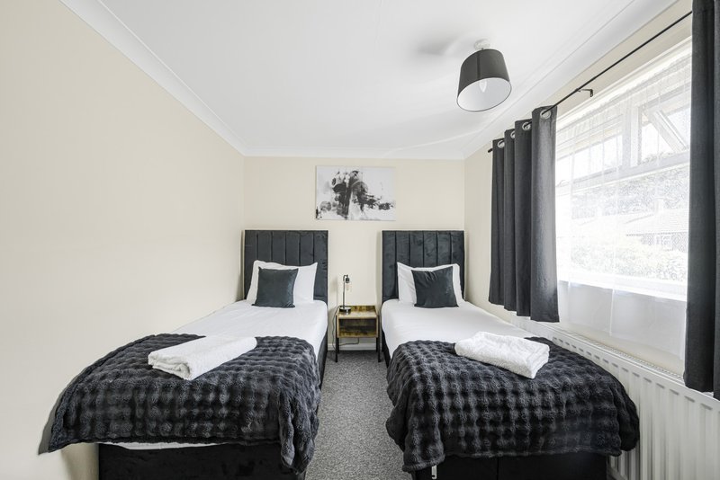 Twin bedroom with two single beds, black headboards, checkered bedding and large windows