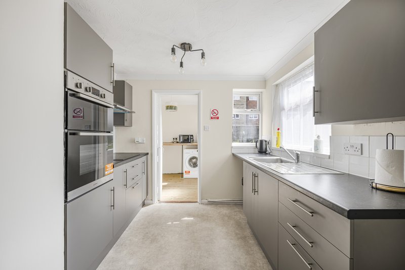 Modern galley kitchen with grey cabinetry, stainless steel appliances and white countertops