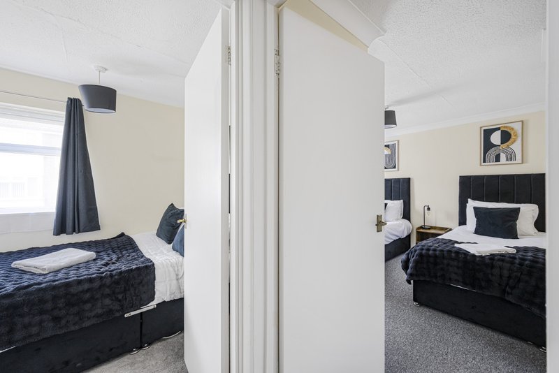 Two twin beds with black headboards and white bedding, separated by white partition wall