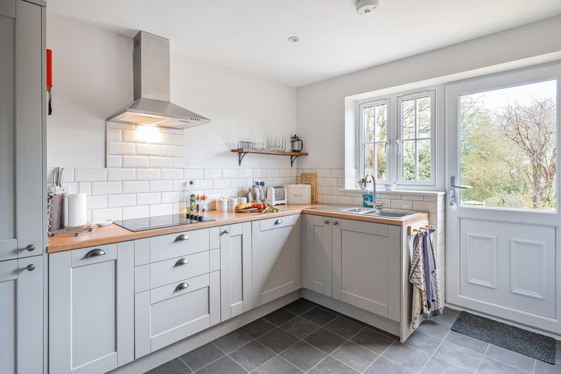 Modern kitchen with white cabinetry, wooden countertops, subway tile backsplash and garden view
