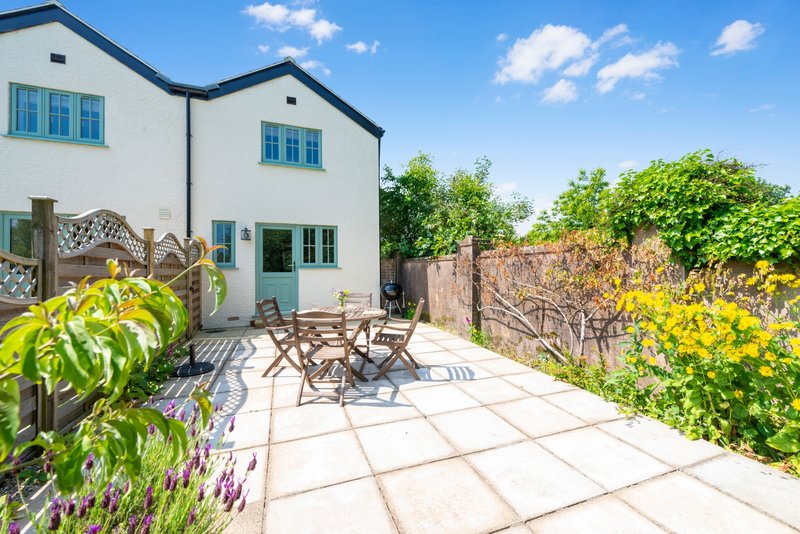 Modern white house with patio area, garden furniture, and landscaped borders