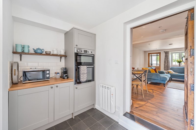 Modern kitchen with white cabinetry, wooden countertop, built-in appliances and open doorway to living area