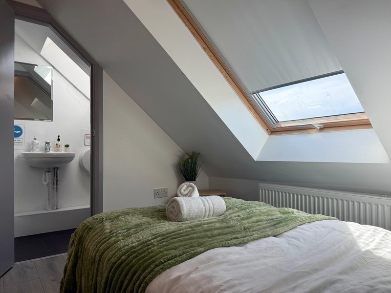 Attic bedroom with double bed, green bedding, ensuite bathroom and skylight window