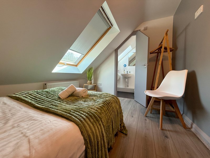 Attic bedroom with skylights, wooden floor, single bed and modern chair