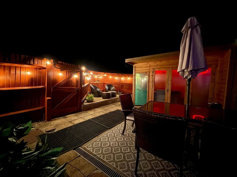 Outdoor patio area at night with string lights, seating, umbrella and geometric rugs