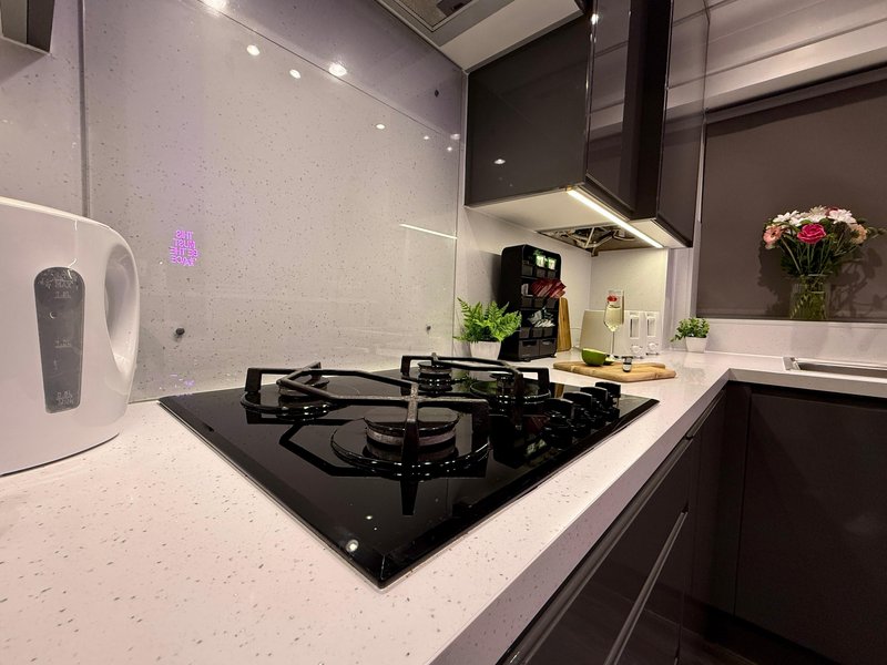 Modern kitchen with black gas hob, white countertop, hood extractor and fresh flowers in vase