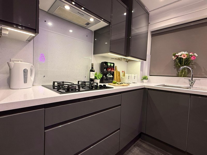 Modern kitchen with dark cabinetry, white countertop, gas hob, and fresh flowers in vase
