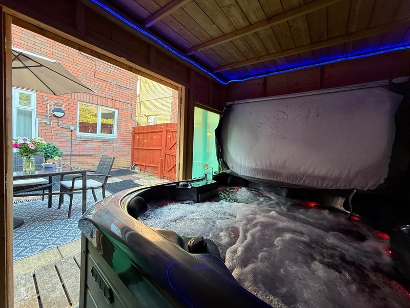 Hot tub interior with blue ambient lighting and view to brick patio with seating area