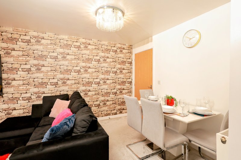 Living room with black leather sofa, brick accent wall, ceiling light fixture and white desk area