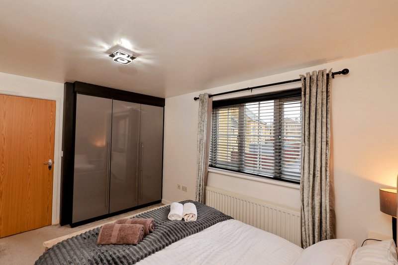 Bedroom with double bed, fitted wardrobe, window with shutters and curtains