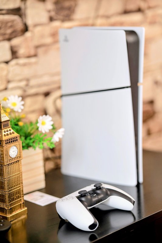 Gaming console with controller, decorative Big Ben model and potted flowers on shelf