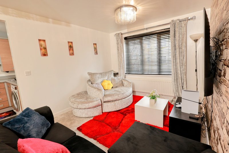Living room with curved sofa, red rug, white coffee table and wall art