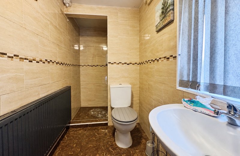 Bathroom with toilet, sink, shower enclosure and beige tile walls