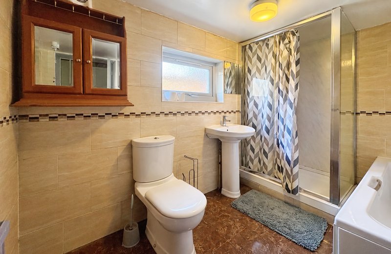 Bathroom with toilet, pedestal sink, shower enclosure and wooden mirror cabinet