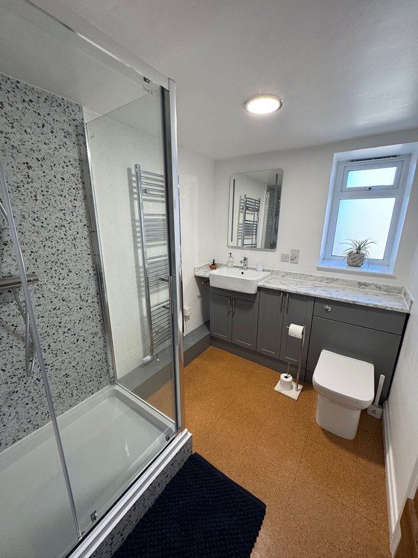 Modern bathroom with walk-in shower, dark vanity, towel rail and window